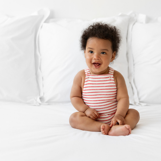 a baby sitting on the bed smiling 