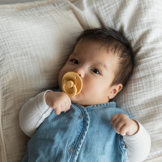 a baby laying down with a bibs pacifier