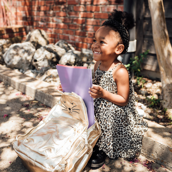 toddler holding her backpack