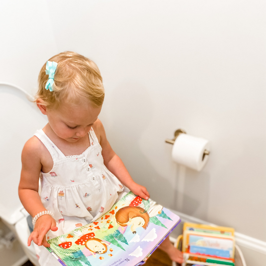 A toddler reading a book while potty training