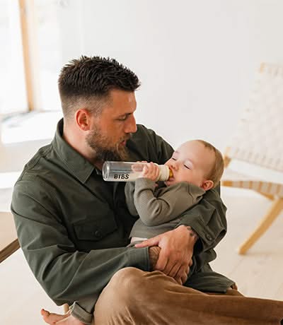 Father holding a toddler drinking milk from a bottle