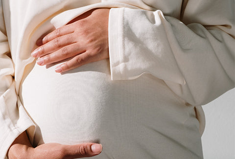 A pregnant woman holds her stomach with her hands