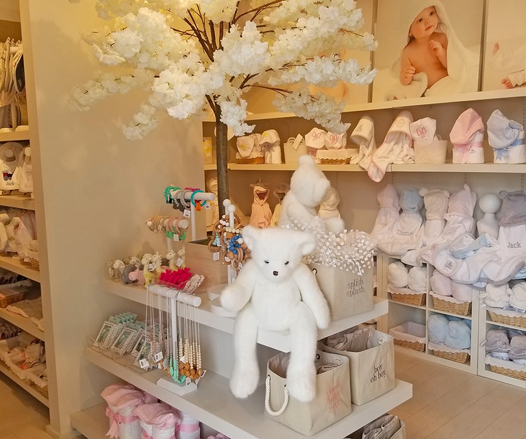 A cozy baby boutique interior featuring shelves stocked with soft toys and baby clothes