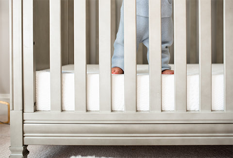 Baby's legs shown behind the crib