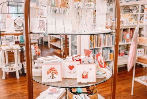 Circular display shelf in a boutique featuring greeting cards, jewelry, and gift accessories