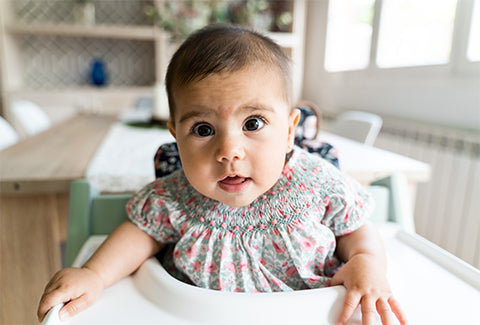 The baby is waiting for food on the highchair