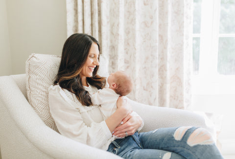 Woman holding a baby on her lap while sitting on an armchair