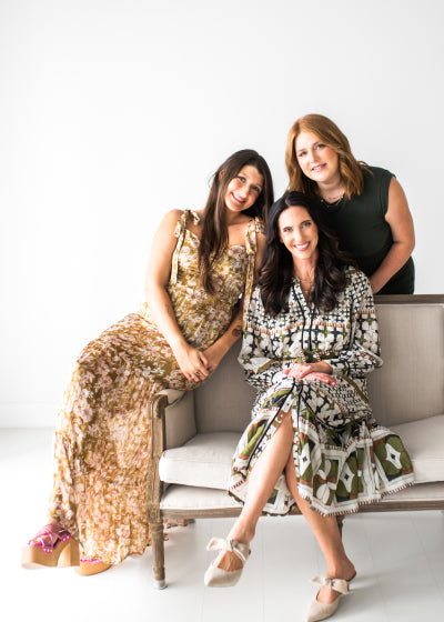 Three women smiling for the camera while seated comfortably on and beside