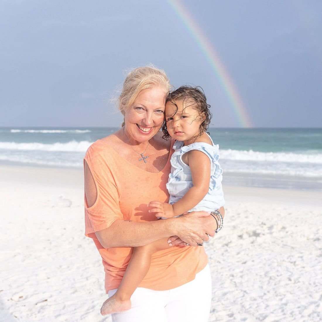 grandma holding granddaughter on beach