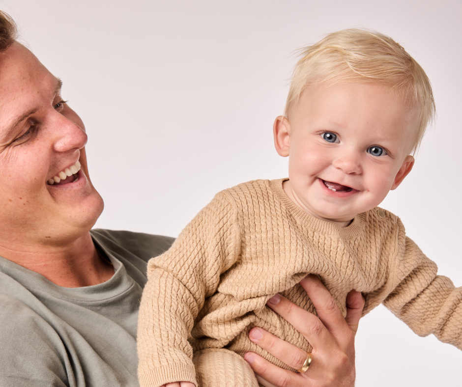 dad holding baby smiling