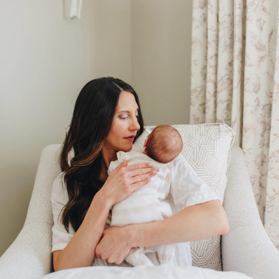 mom holding baby upright in bright nursery