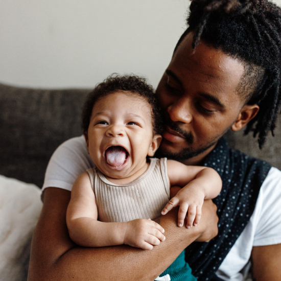 Dad holding his baby who is smiling 