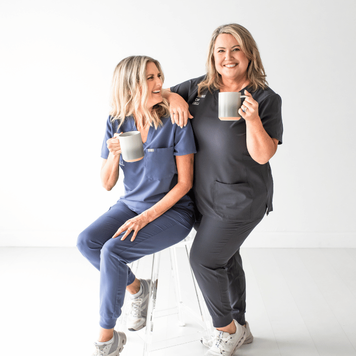 Two smiling women pose with coffee in their hands