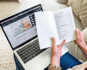 Woman is reading a book and taking a baby course on a laptop 1