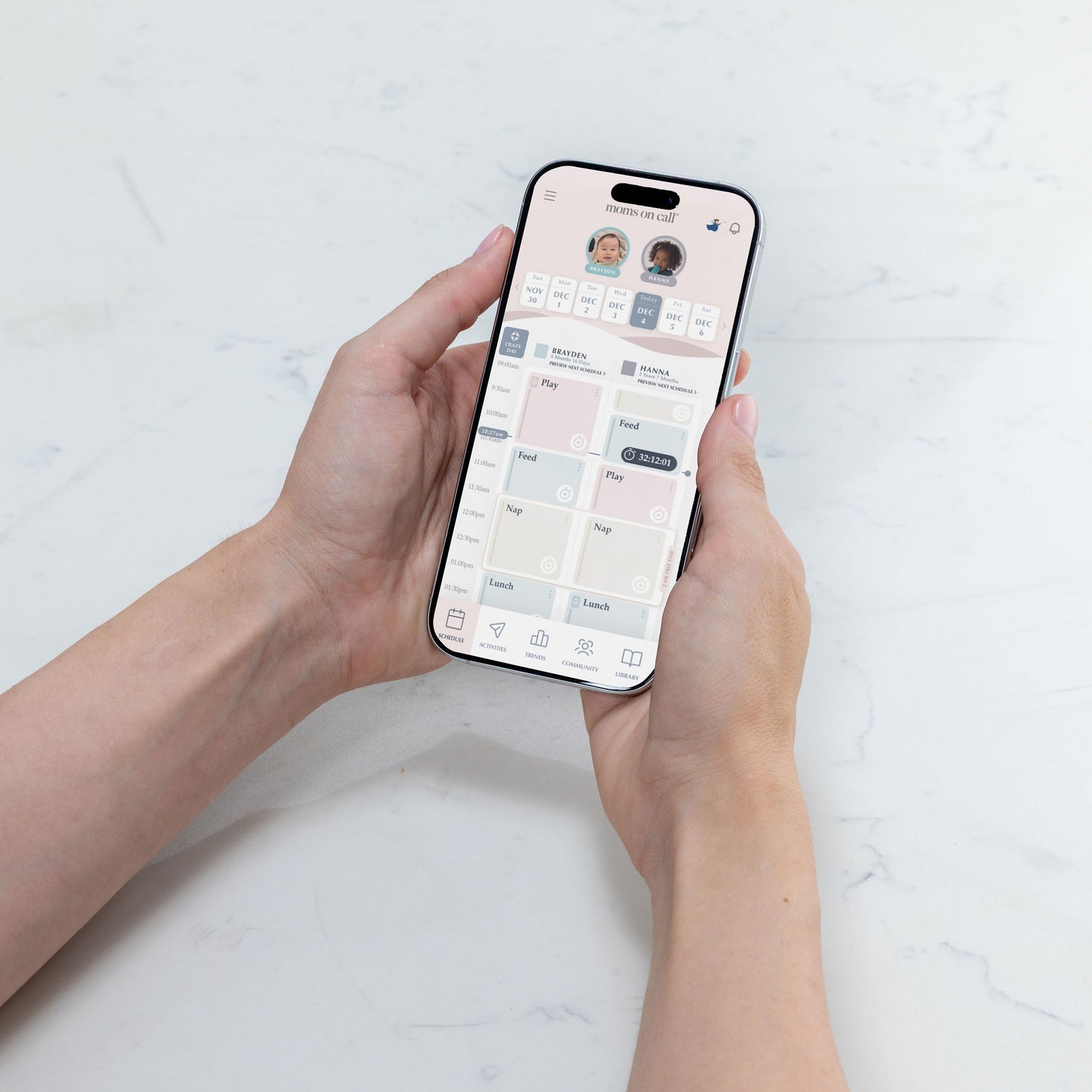 Person holding a smartphone with The Moms on Call App schedule