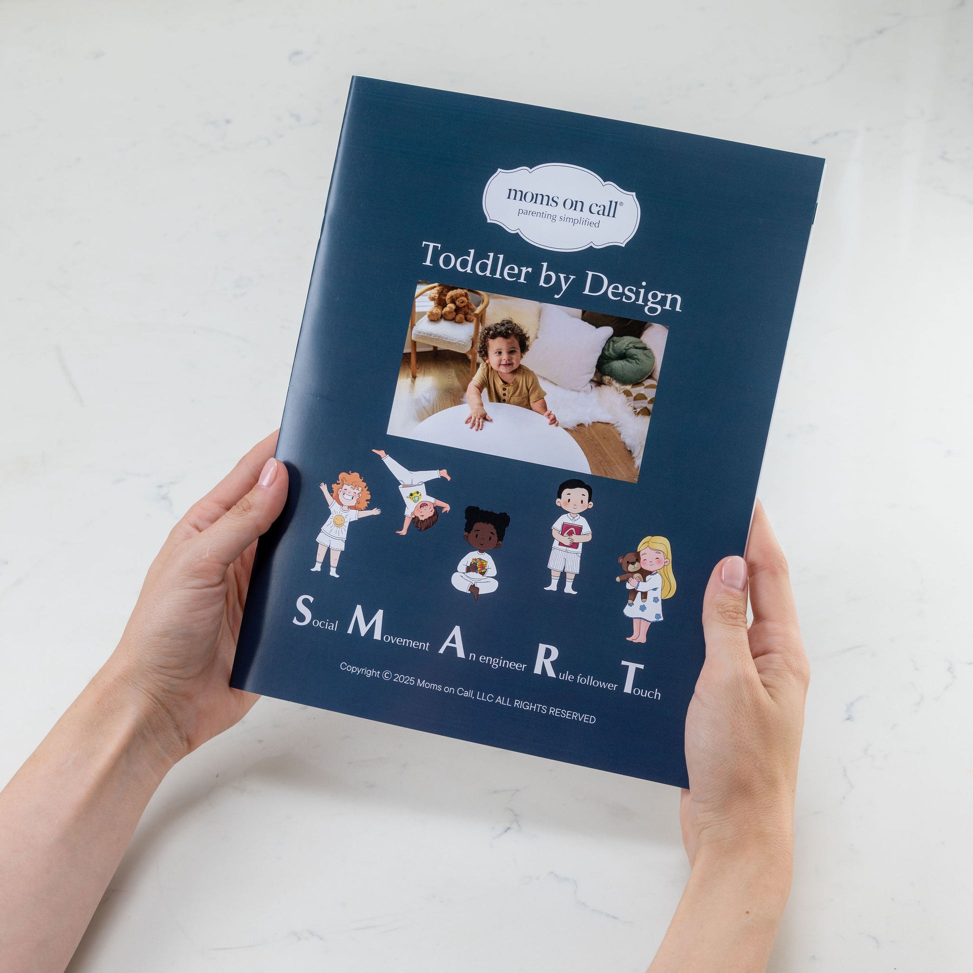 Book titled 'Toddler by Design' held by a person on a light background