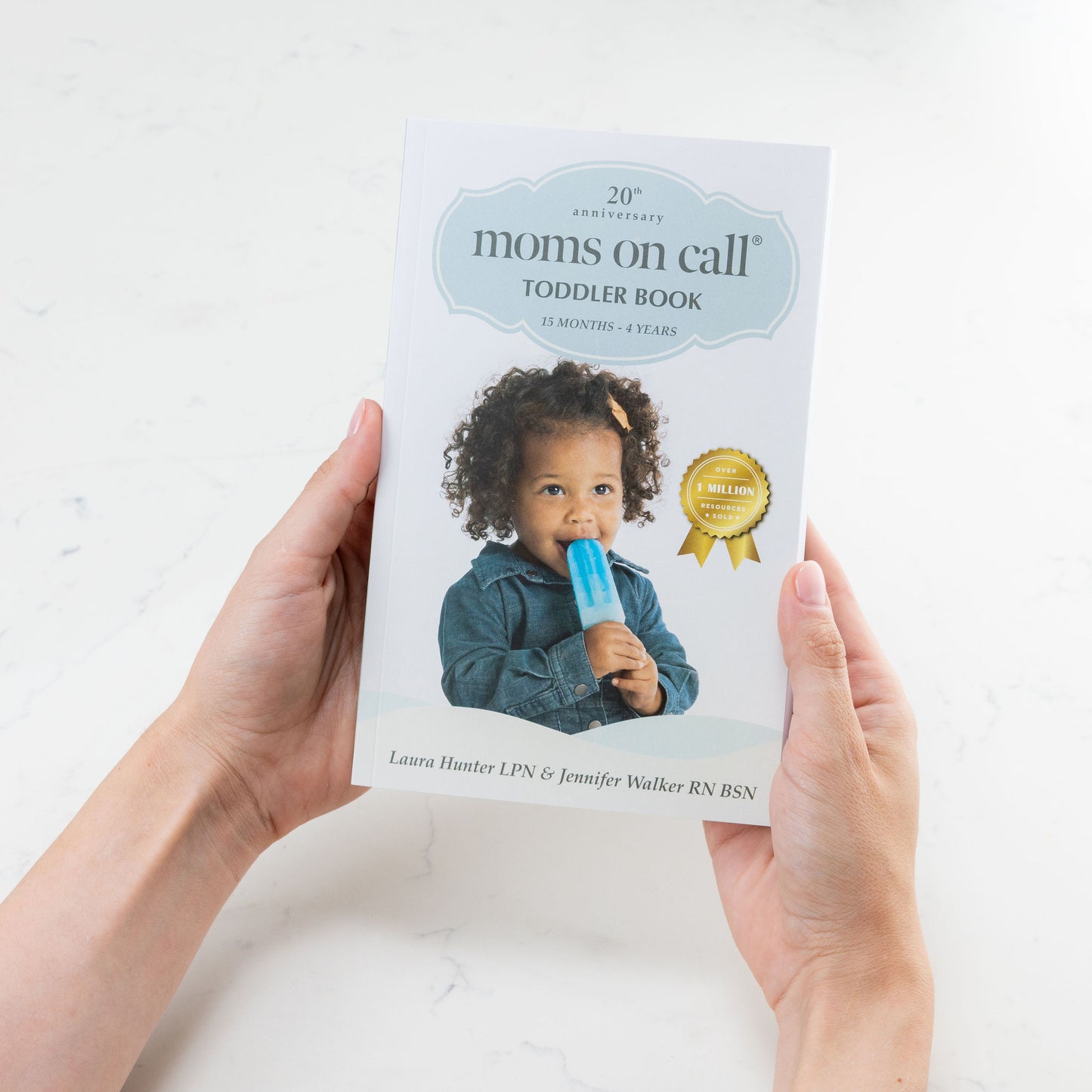 Book titled 'moms on call' held by a person with a white background